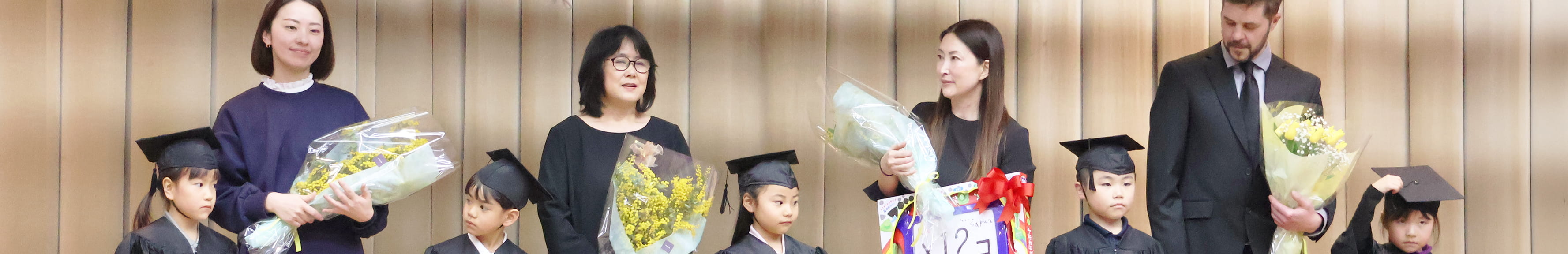 遠足に出かけた旅先で集合写真をとるフランクリンスクール倉敷校の生徒と講師の男性