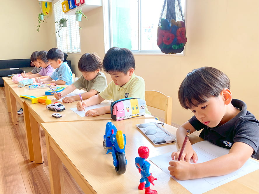 目の前に車のおもちゃや剣のおもちゃを置いて、それを見ながら名前を英語で書いていく生徒たち