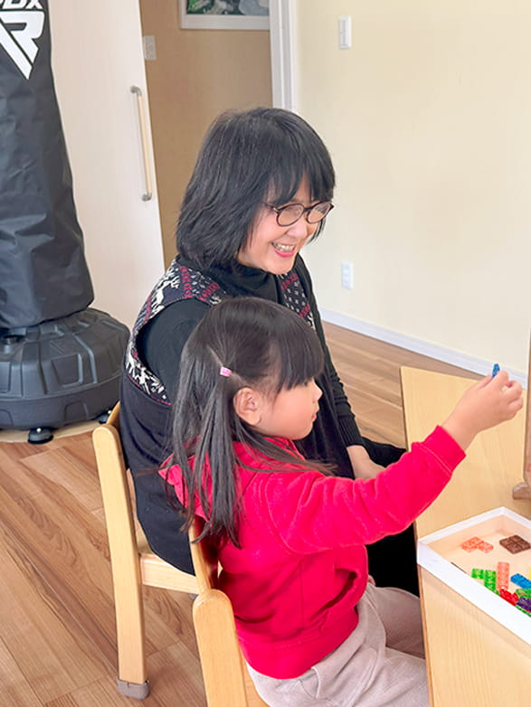 生徒と一緒にブロックを使って遊んでいる保育士の女性