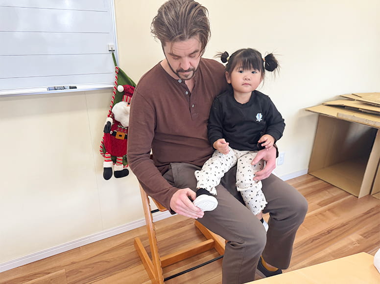 生徒を膝の上に乗せてシューズを履かせている講師の男性