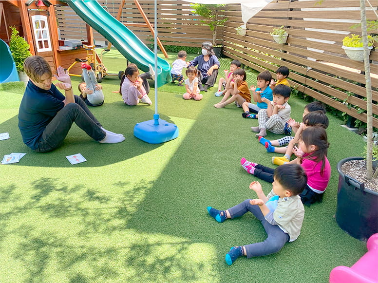 フランクリンスクール倉敷校の広い敷地内で英語のレッスンをする講師と生徒たち