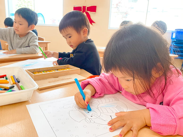 真剣な表情で雪だるまの塗り絵をしている生徒たち