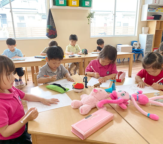 ピンクのぬいぐるみや動物のおもちゃを見ながら、単語を書いている生徒さん
