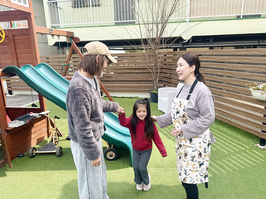 子どもを抱いた保護に笑顔で話しかける保育士