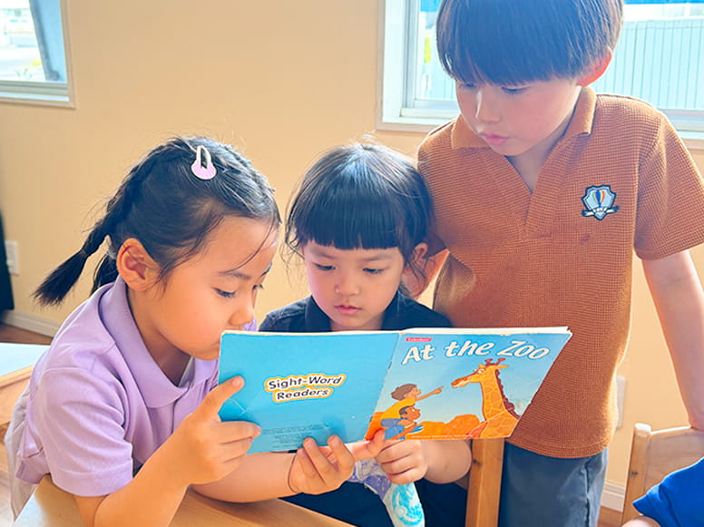 動物の絵本を真剣な表情で読んでいる3人の生徒たち