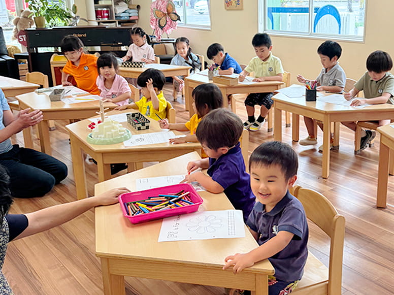 一人ずつ椅子に座り紙に書かれた花を色鉛筆で縫っていく生徒たち