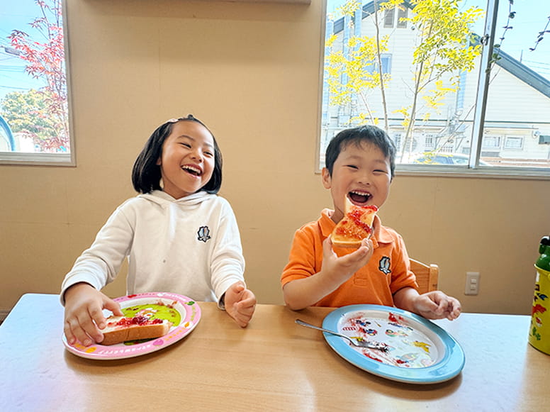 笑顔いっぱいでスナックタイムのパンを頬張る生徒たち