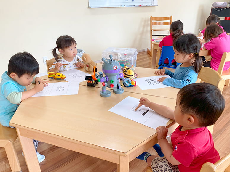 鉛筆をもって線をなぞる練習や色を塗っていくなどをしている生徒たち