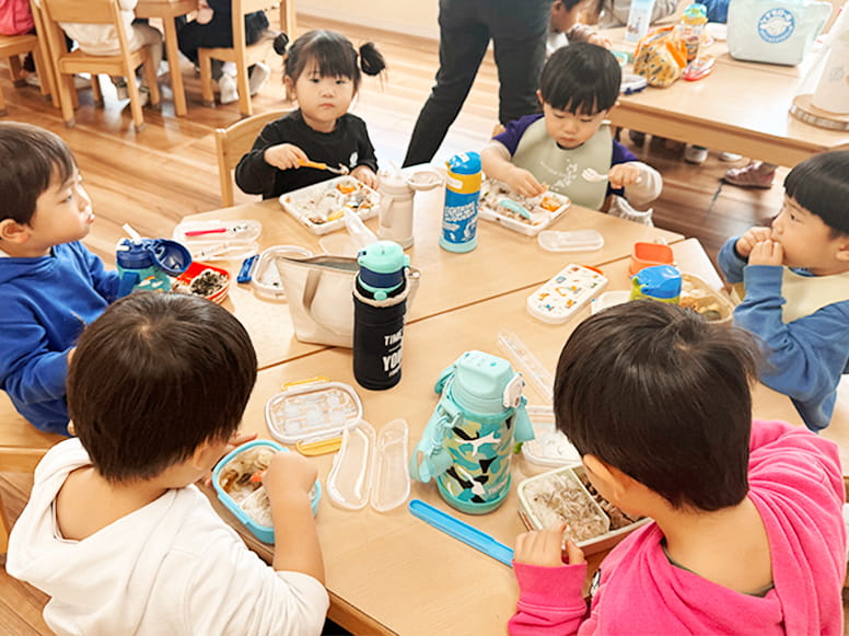 美味しそうなお弁当をテーブルいっぱいに広げて食べる生徒たち